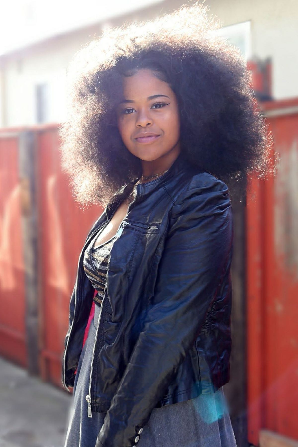 Dejah Vú in a black leather jacket, backlit by afternoon sun