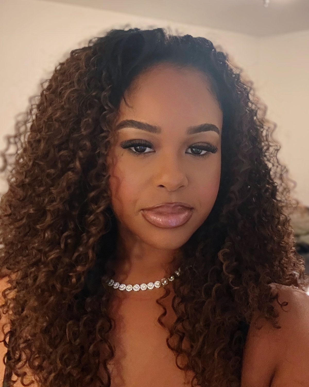 Portrait of Dejah Vú with long curly hair and a diamond necklace