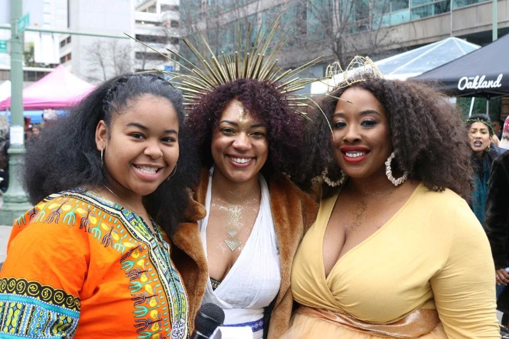 Dejah Vú with two guests at an outdoor community event, holding a microphone